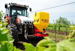 Single disc spreader  ES 100 M1 Classic, which ist mounted in front of the tractor and drives in the wineyard